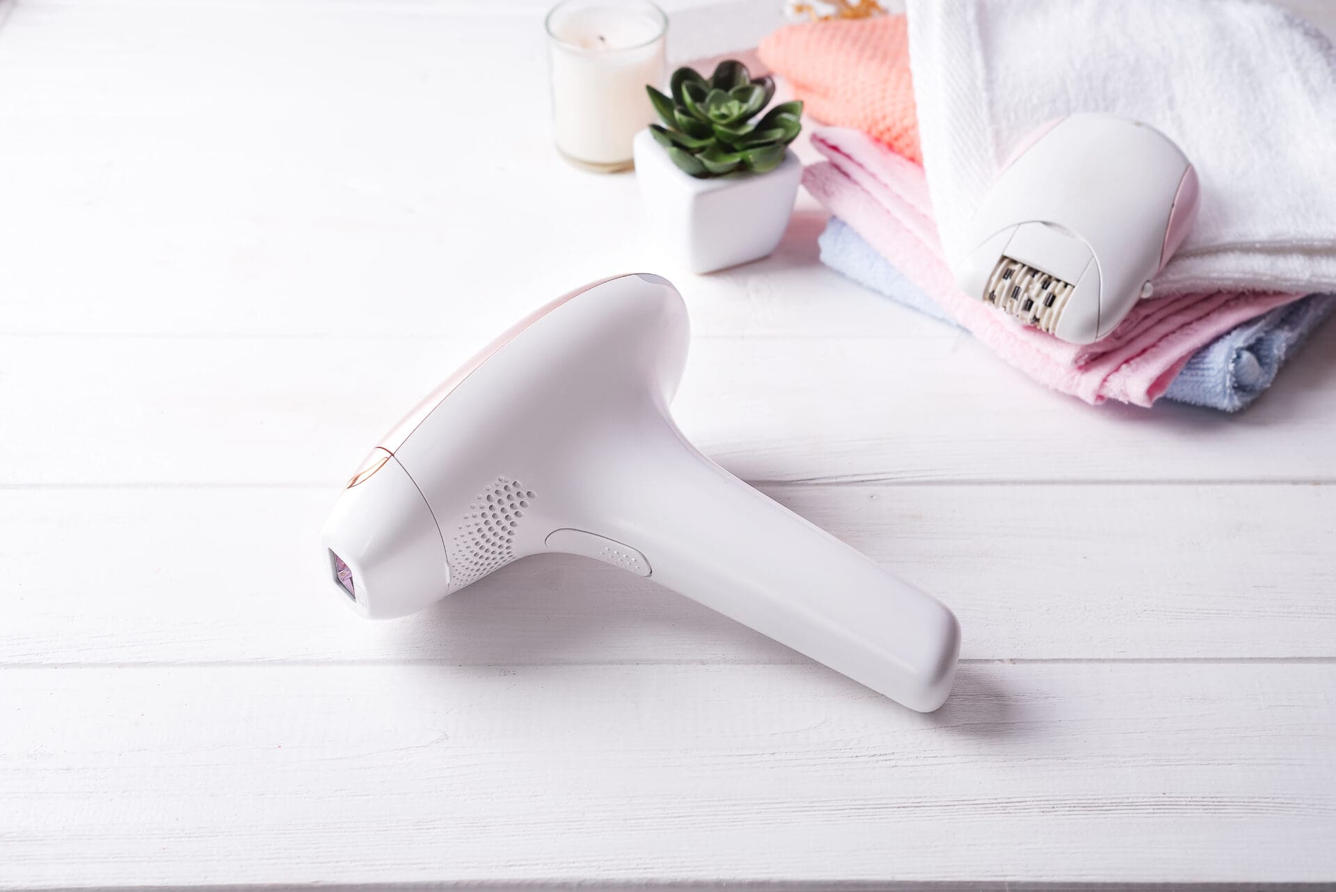 set of means of hair removal. Modern epilators in bathroom on a white wooden background.